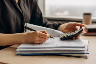 Personne faisant des calculs à la calculatrice sur des documents administratifs