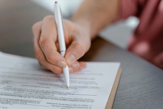 Main signant un contrat au stylo sur un bureau