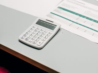 Calculatrice posée à côté d'un tableau de chiffres sur un bureau