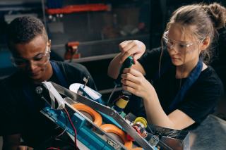 Deux élèves en atelier assemblant un robot pédagogique, tournevis en main