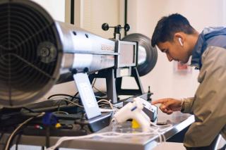 Étudiant réglant un banc d'essai de soufflerie dans un laboratoire d'école d'ingénieurs