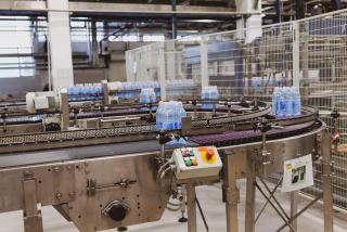 Ligne de production automatisée de bouteilles d'eau sur convoyeur en inox