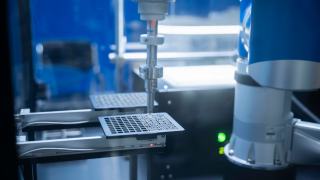 Robot industriel manipulant une pièce dans une cellule automatisée sous éclairage bleu