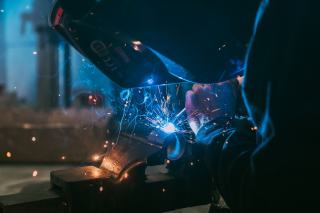 Soudeur casqué au travail, arc électrique bleu et étincelles