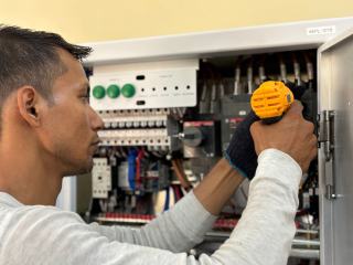 Technicien de maintenance intervenant à la visseuse dans une armoire électrique