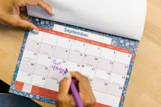 Main entourant des dates sur un calendrier du mois de septembre