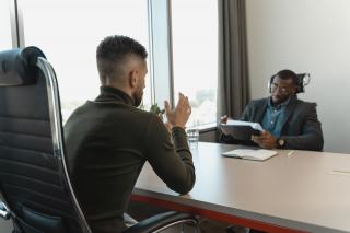 Échange entre deux personnes assises de part et d'autre d'une table de réunion